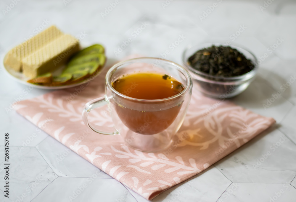 Green tea with jasmine in a transparent mug on a light background. Horizontal orientation