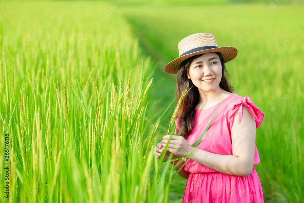 Beautiful and pretty Asian girl in vintage pink dress enjoy relaxing in the beautiful rice field close up.  Pretty Asian girl's portrait in rice farm.  Vintage girl's portrait.