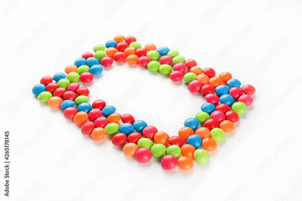 Frame of multi-colored candies close up. Rainbow colored dragee multicolored glaze on a white background Frame of multi-colored candies close up. Rainbow colored dragee multicolored glaze on a white background