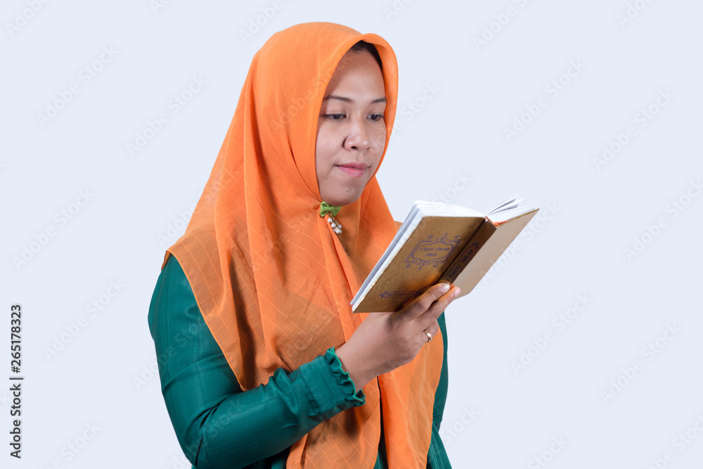Portraits of young Asian Muslim business women wearing hijab And Reading The Holy Quran, isolated on white background Portraits of young Asian Muslim business women wearing hijab And Reading The Holy Quran, isolated on white background