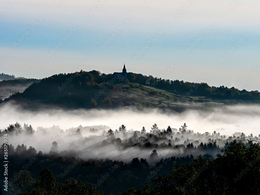 Church on the hill and beautiful white fog with sun rays, Alsace