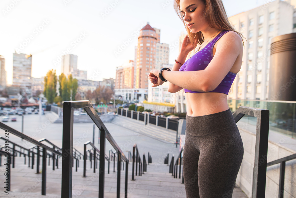 Sports girl in leggings and a sports bra is standing on the street in the  background