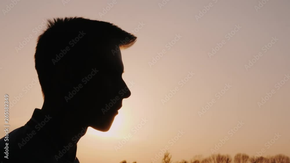 Profile of a teenager, eating snacks. Silhouette against the setting sun