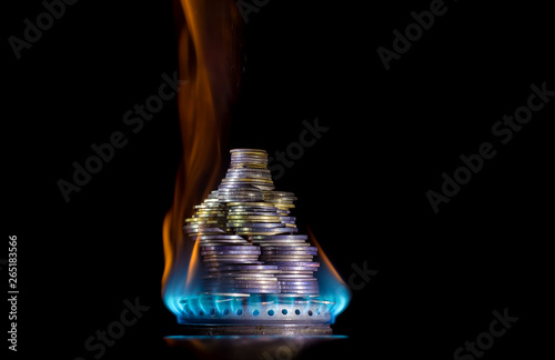 Coins on fire. The concept of high prices for natural gas. Blue flame of burning natural gas from a gas stove with Ukrainian coins.