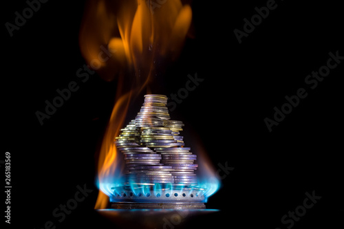 Coins on fire. The concept of high prices for natural gas. Blue flame of burning natural gas from a gas stove with Ukrainian coins.