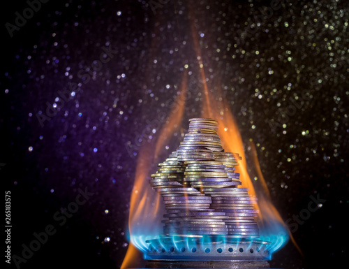 Coins on fire. The concept of high prices for natural gas. Blue flame of burning natural gas from a gas stove with Ukrainian coins.