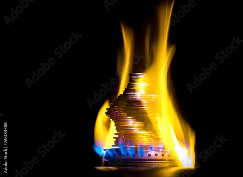 Coins on fire. The concept of high prices for natural gas. Blue flame of burning natural gas from a gas stove with Ukrainian coins.
