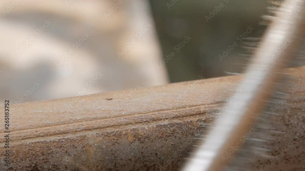 Close-up of a man's hands in work gloves, cleaning the old pipe from rust with a metal brush.