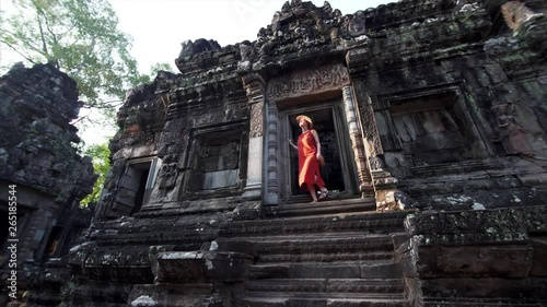 Sliding view from below of woman coming out from the Chau Say Tevoda temple and looking around. Angkor Wat complex, Cambodia