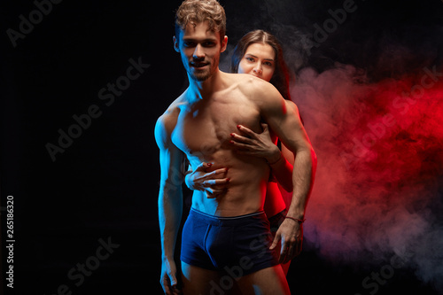 young couple expressing their warm feeling, passion . close up photo. isolated black background. red smoke in the background © the faces