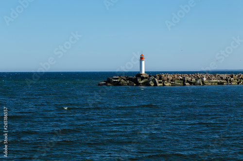 White lighthouse tower on blue sky background