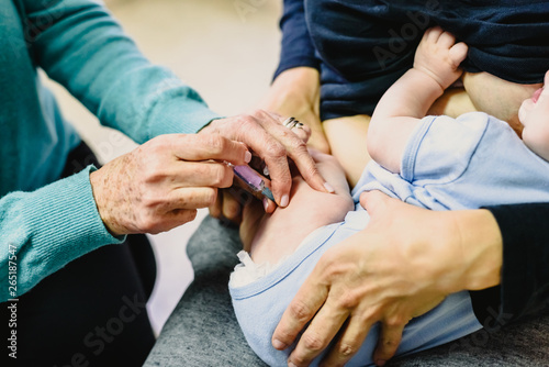 Real baby being vaccinated with a syringe in the thigh by a pediatrician doctor to avoid the spread of diseases.