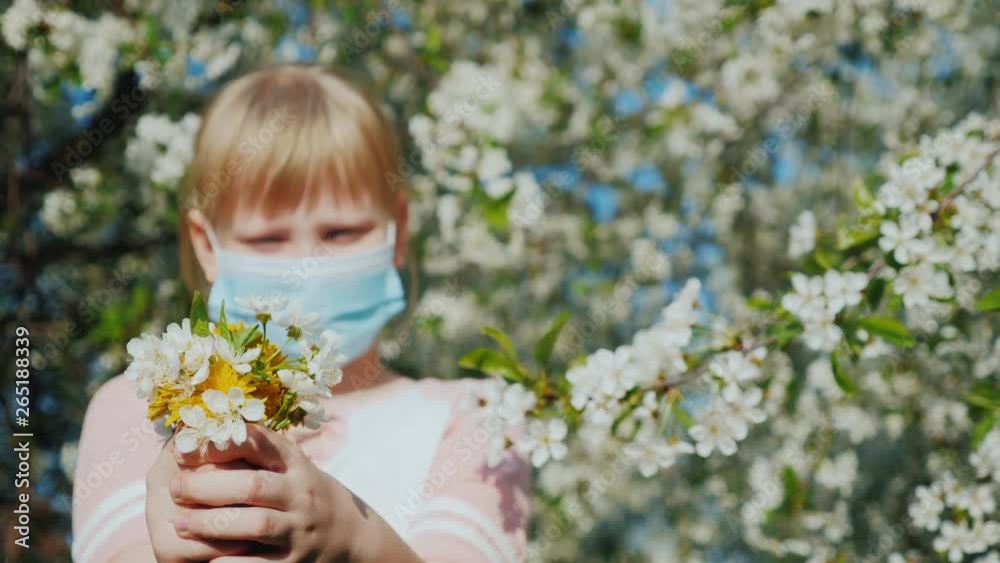 Little girl with a bouquet of flowers and a mask on the background of flowering trees Little girl with a bouquet of flowers and a mask on the background of flowering trees