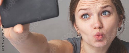 Obraz na plátně Portrait of selfie addict happy charming beautiful and excitingyoung woman taking self portrait photo using smart phone