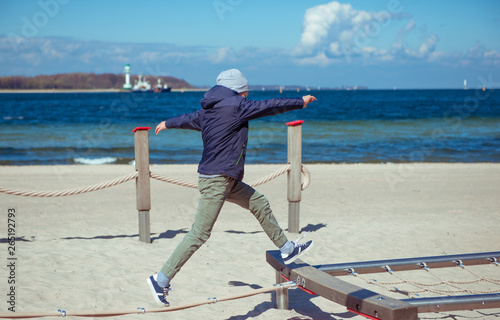 Handsome teenager playing at pllayground on sunny beach photo