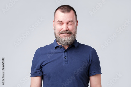 Fotografi Mature man in blue shirt wrinkled due to sour taste.