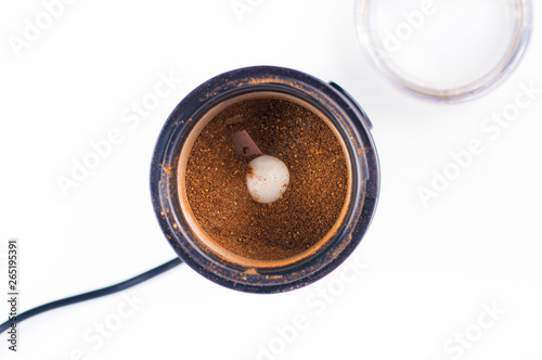 coffee grinder on white background with ground coffee inside