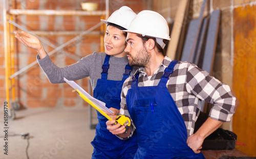 Workers man and woman discuss construction plan