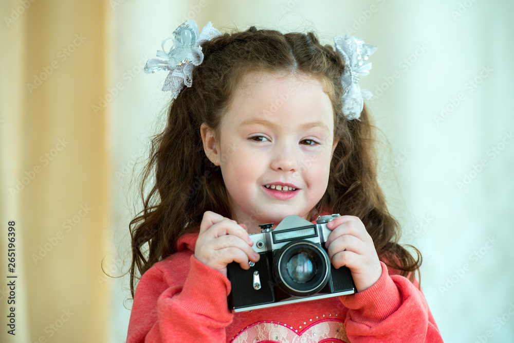 Little girl with vintage camera on light background. Smiling cute kid girl 4-5 year old