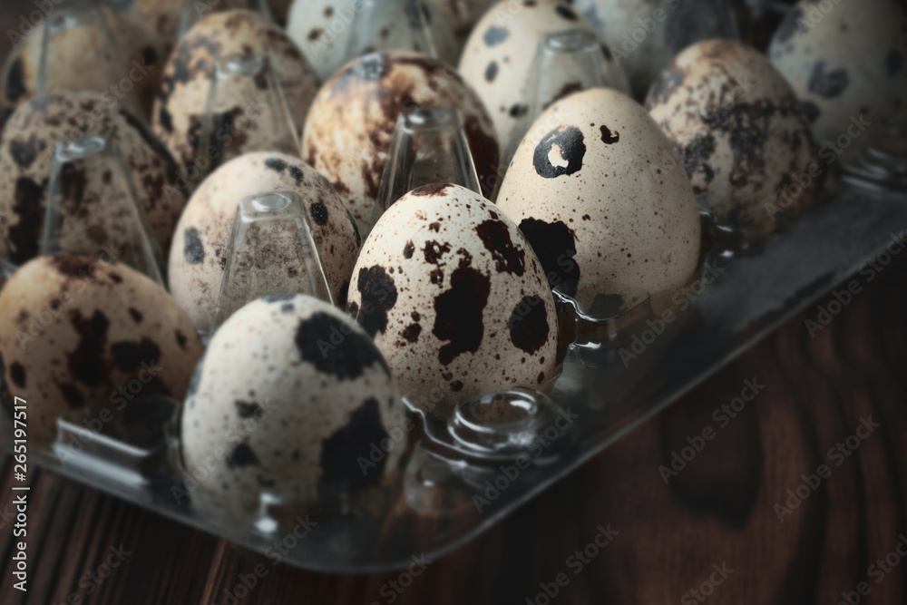 Plastic container with quail eggs on a wooden table Plastic container with quail eggs on a wooden table