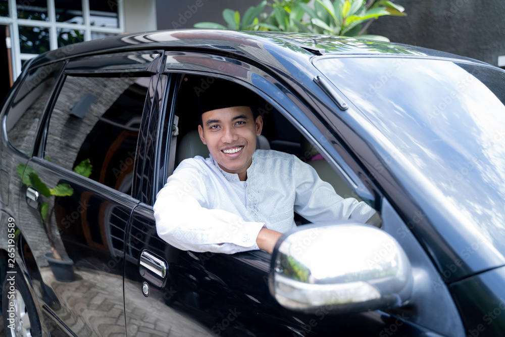 handsome muslim asian man with head cap driving a car