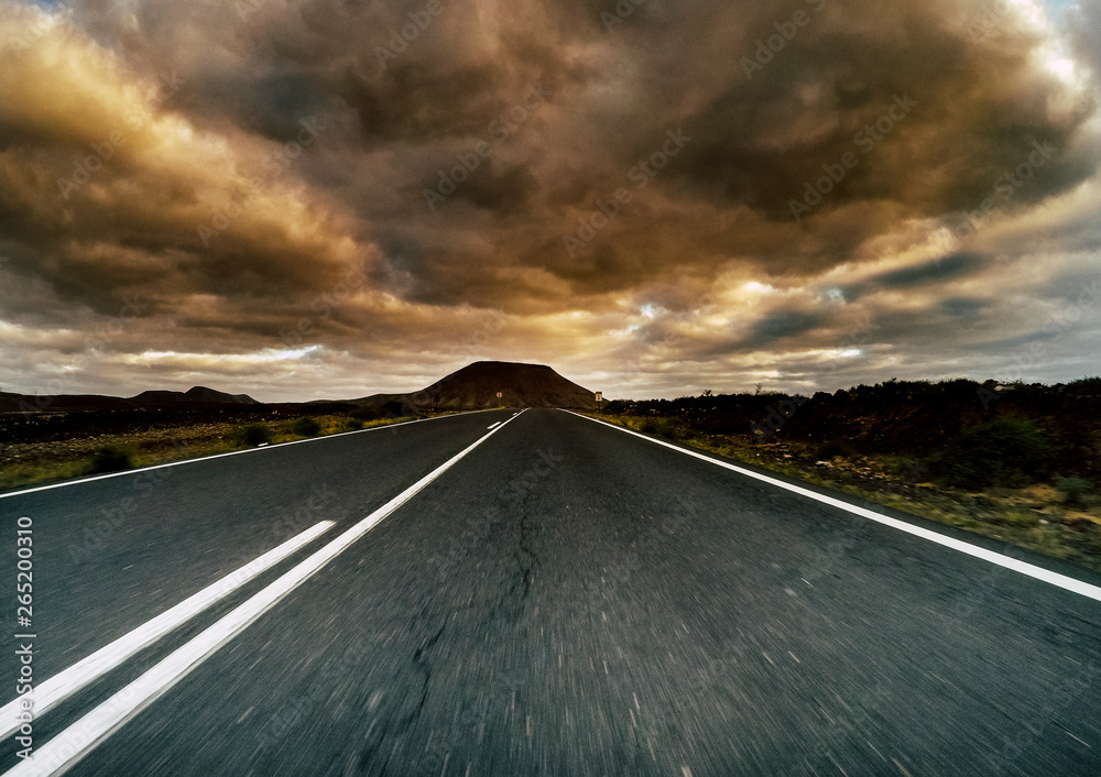 Long way road viewed from ground and dramatic cloudy sky in background - travel and car movement transportation concept