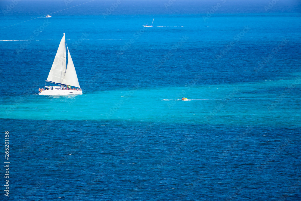 Velero de dos velas navegando en el mar caribe con contraste colores azul turquesa, Cancun, Mexico 