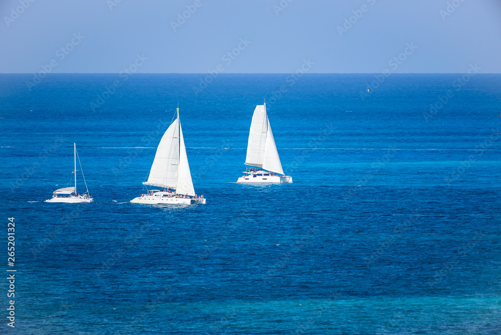 Grupo de Veleros de dos velas en competencia regata en el mar caribe con contraste colores azul turquesa, Cancun, Mexico 