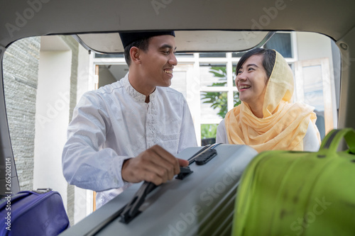 portrait of muslim asian couple put suitcase in the car trunk