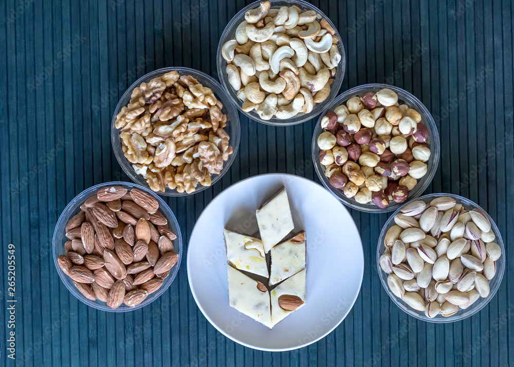 Oriental dessert halva with pistachio, almond, cashew nuts, peanut, walnut on a plate. Image. Healthy food. Nuts mix assortment. sweets, Turkish Delight. Isolated background.. Eastern delicacy Oriental dessert halva with pistachio, almond, cashew nuts, peanut, walnut on a plate. Image. Healthy food. Nuts mix assortment. sweets, Turkish Delight. Isolated background.. Eastern delicacy