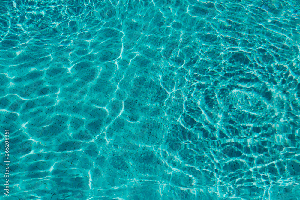 Ripple blue water in swimming pool with sun reflection.