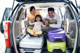 muslim family with kid sitting in the car trunk with suitcase. eid mubarak or idul fitri mudik