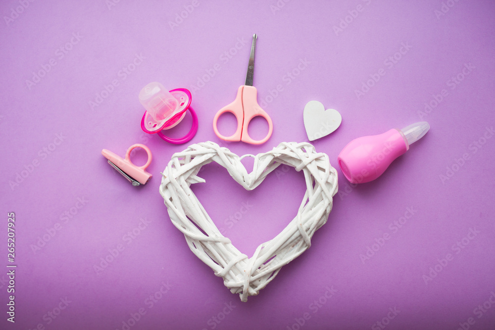 Newborn baby story. Strow heart and children's toys, scissors, baby bottle, nipple, hairbrush on violet background