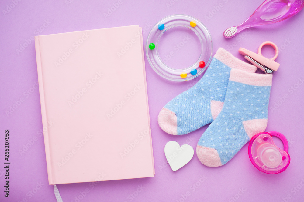 Newborn baby story. Strow heart and children's toys, scissors, baby bottle, nipple, hairbrush on violet background