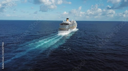 Back of the cruise ship and its beautiful wake on the blue sea surface, seascape. Stock. Aerial view of a beautiful white cruise liner in a sunny day on blue cloudy sky background. photo