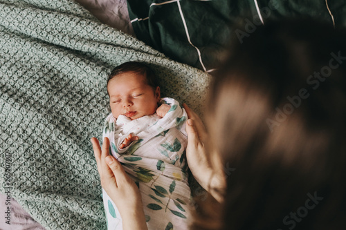 young mother swaddling a newborn baby photo
