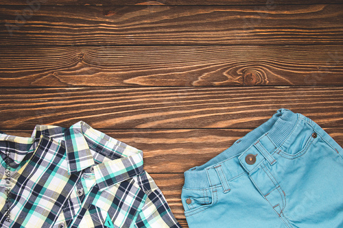 Set of children's clothing for the boy. Blue pants and shirt on wooden background. Horizontal color photo