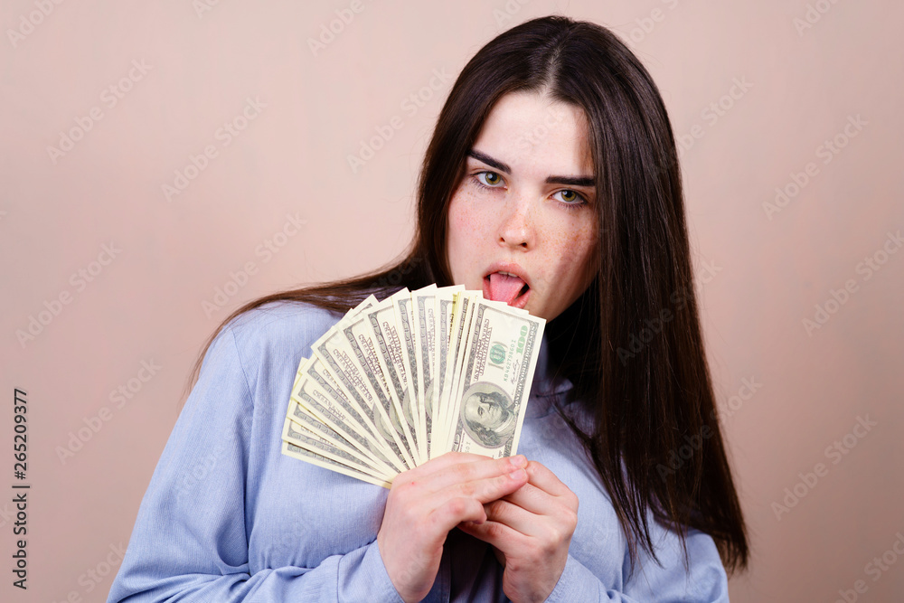 Savings, earning, money and banking, purchases and shopping. Beautiful young woman joyfully holding in her hand a lot of dollars Savings, earning, money and banking, purchases and shopping. Beautiful young woman joyfully holding in her hand a lot of dollars