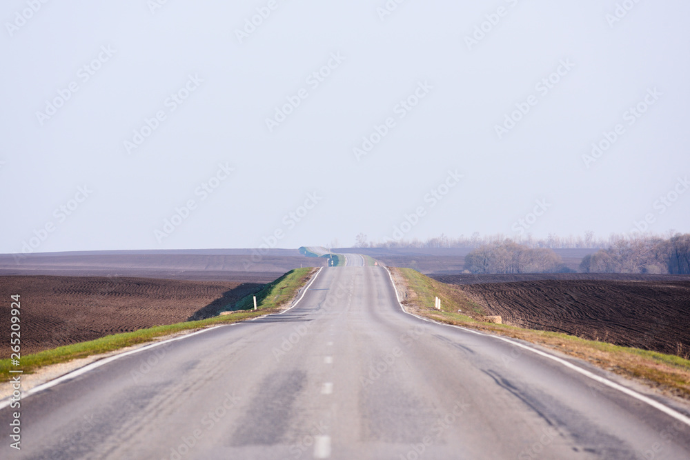 Serene countryside lanscape. Empty asphalt road in empty fields and clear sky in sunny day copyspace. Traveling concept