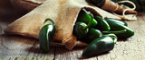 Green jalapeno peppers, old wooden kitchen table background, selective focus