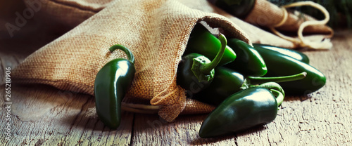 Green jalapeno peppers, old wooden kitchen table background, selective focus photo