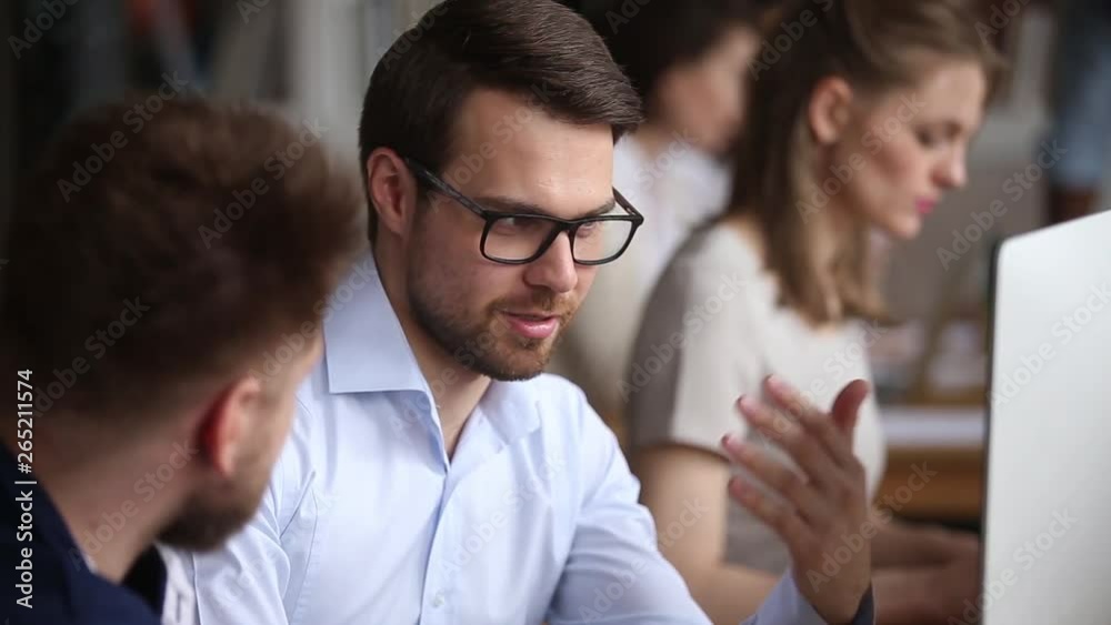 Serious male employees working together discussing computer project in office