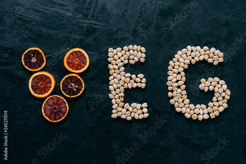 Food letters. Garbanzo and slice of citrus fruit in form of veg letters on dark background. Organic ingredients for vegetarians. Healthy products photo