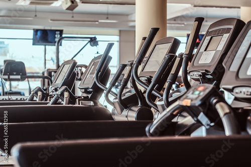 Photo of empty treadmills in gym. There are screen at background.