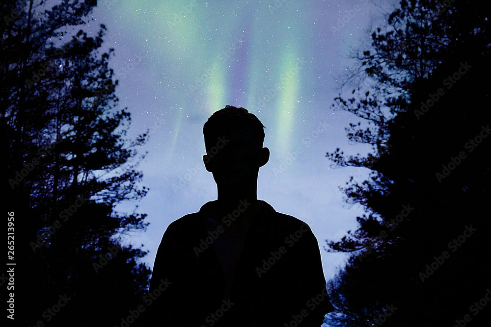 silhouette of boy under the stars and northern lights silhouette of boy under the stars and northern lights