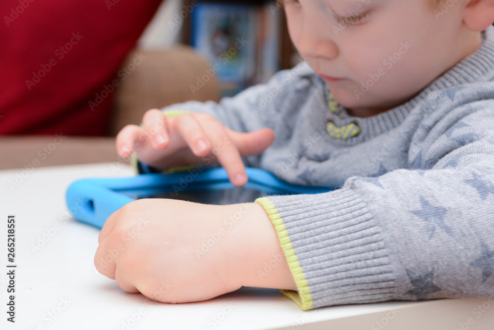 Happy young child is using a tablet computer. Boy is playing with device at home on sofa Happy young child is using a tablet computer. Boy is playing with device at home on sofa