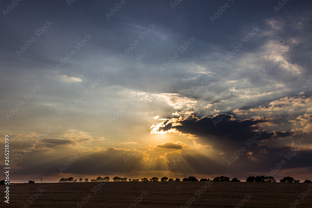 Dramatic clouds and sunset with a combine harvester in a field