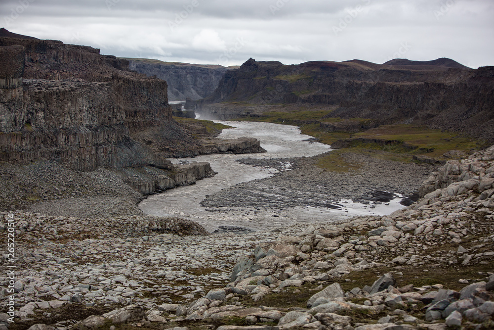A meandering river flows in a valley between volcanic rocks.