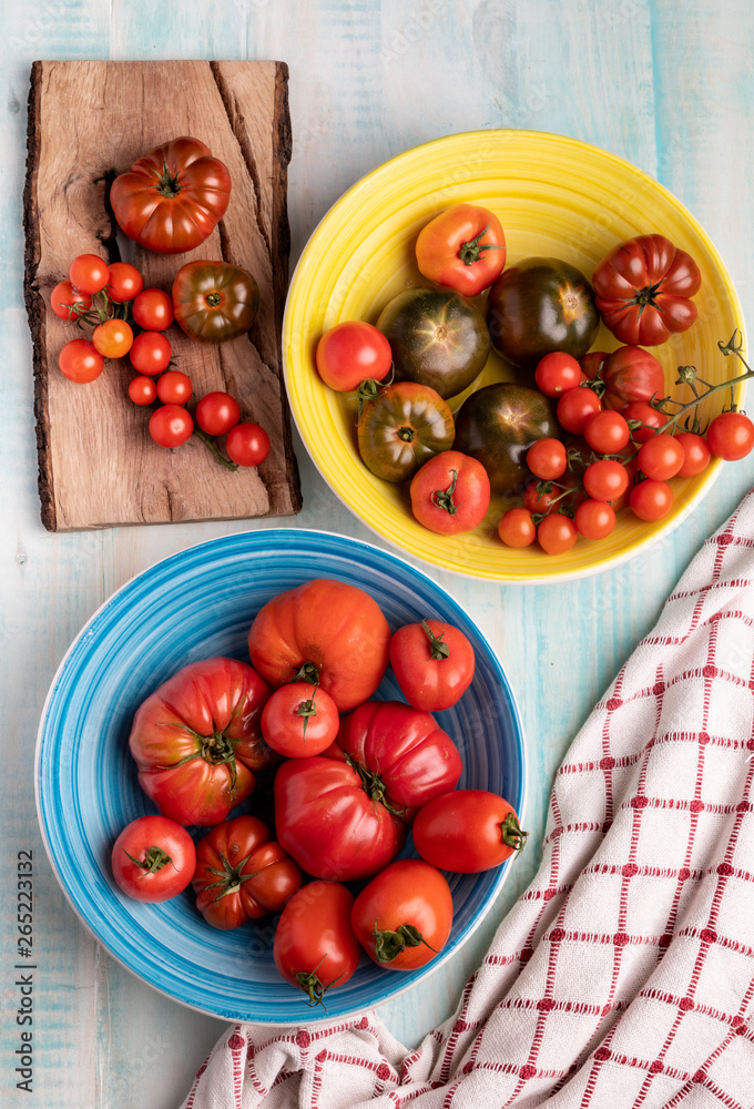 Cloth napkins placed on wooden table near ceramic bowls and lumber board with fresh red tomatoes Cloth napkins placed on wooden table near ceramic bowls and lumber board with fresh red tomatoes