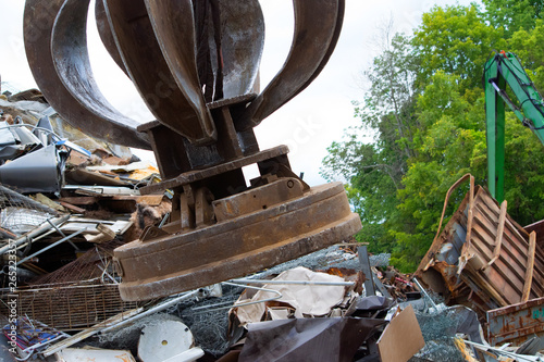 A powerful electromagnet hovers over a pile of metal scrap in salvage yard photo